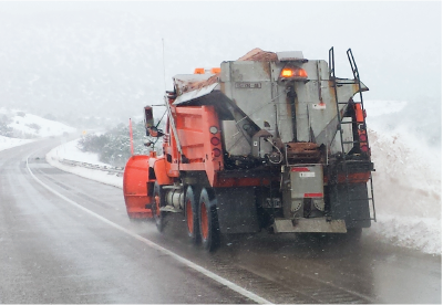 Snow plow applying Ice Slicer to a winter road